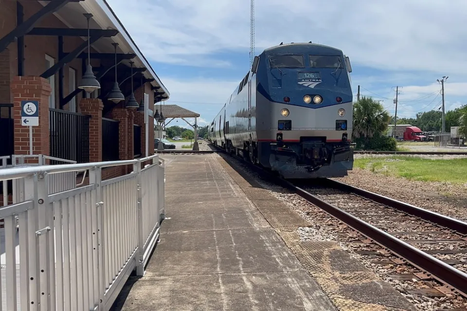 Blue and silver Amtrak train at small station.